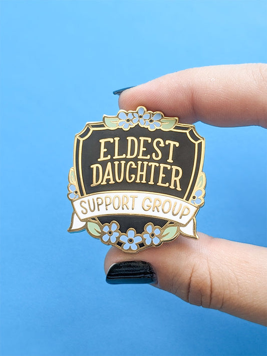 Eldest Daughter Support Group enamel pin black shield with blue flowers
